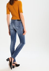 Jeans ajustados en denim azul claro, con un diseño clásico de cinco bolsillos, ligeras desgastes y una cintura de altura media.