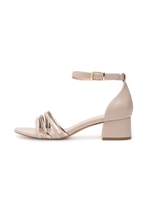 Beige potiņi ar potīšu siksnām, kuriem ir trīs šauras siksnas, aizvērt aizmuguri un bloku papēdi. Gluda materiāla ar maigu spīdumu un zelta sprādzi.