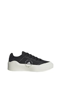 Baskets basses noires avec semelle blanche épaisse, lacets noirs, et texte de logo blanc circulaire sur le côté indiquant "Stella McCartney."