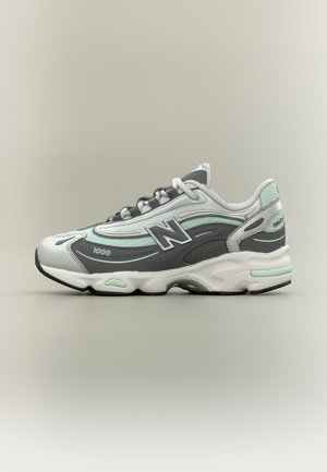 Chaussure de course blanche, grise et vert menthe avec le logo "N", design à lacets et semelle rembourrée, vue de profil sur un fond neutre.