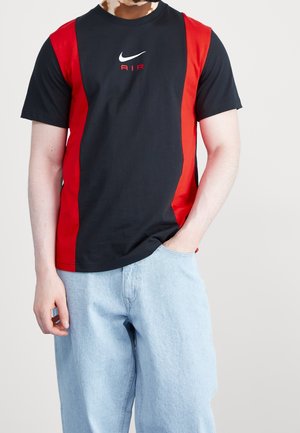 Schwarzes und rotes Nike-T-Shirt mit kurzen Ärmeln, mit einem zentralen Logo und einem horizontalen Farbblockdesign. Weiches Baumwollmaterial.