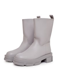 Botines de cuero gris con suela gruesa, acabado liso y dos tiradores en la parte trasera para facilitar su uso. Diseño con punta cuadrada.