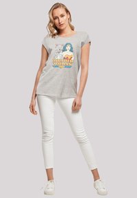 Grå bomulls T-skjorte med et fargerikt Wonder Woman-trykk. Kombinert med hvite tettsittende jeans og hvite sneakers.