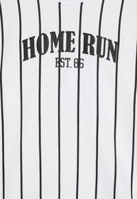 Vit t-shirt med svarta vertikala ränder, med texten "HOME RUN" och "EST. 86" i fet svart skrift. Slät bomullstextur.