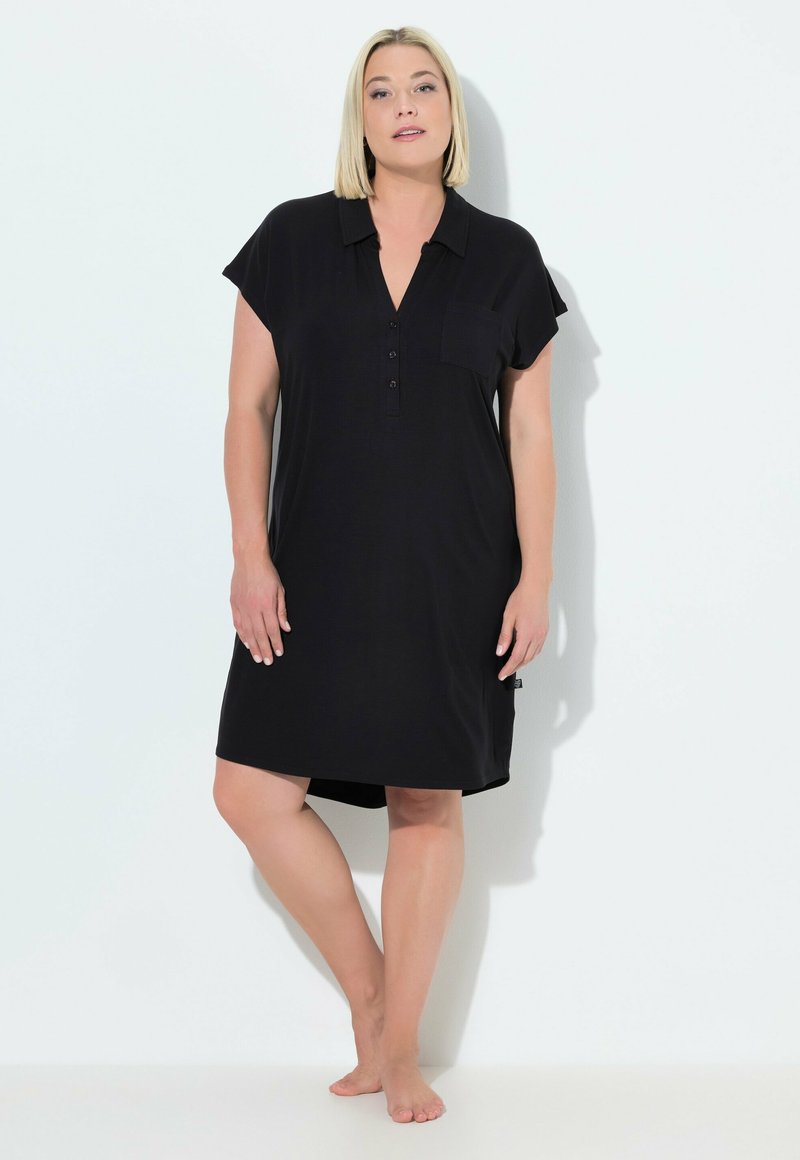 Vestido negro de manga corta con tapeta de botones, bolsillo en el pecho y dobladillo ligeramente redondeado. Tejido suave con un corte holgado.