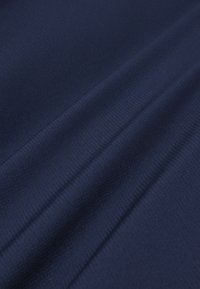 Tela azul oscuro con textura de fina cuadrícula y pliegues suaves que crean sombras y reflejos sutiles en toda la superficie.