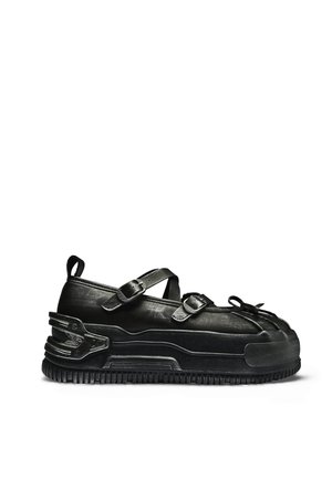 Zwarte leren sneaker met dikke zool, twee gespen over de bovenzijde, afgeronde verstevigde neus en een trekband aan de hiel.