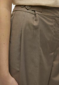 Pantaloni marrone a vita alta caratterizzati da un design plissettato, due chiusure a bottone e una superficie liscia, che offrono un'estetica su misura.