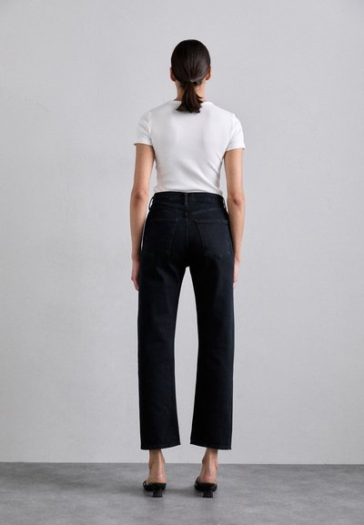Black wide-leg denim jeans with rear pockets and a high waist; paired with a fitted white short-sleeve ribbed top.