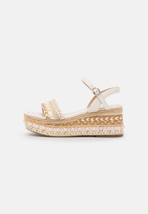 Sandale compensée beige avec plateforme en jute tressée, deux brides avant tissées et bride de cheville réglable avec boucle argentée.