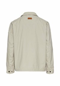 Lys beige jakke med krave, knapmanchetter og et lædermærke på bagsiden. Har en afslappet pasform og et glat, struktureret stof.
