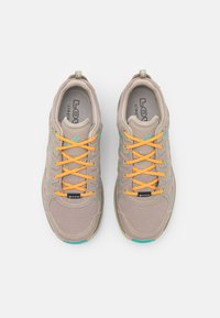 Scarpe da ginnastica beige con tomaia in rete e tessuto, lacci arancioni, dettagli turchesi, colletto imbottito e suola antiscivolo testurizzata.