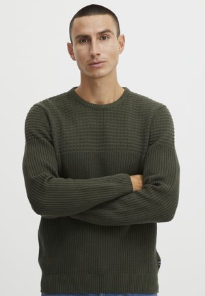Pull en tricot vert avec un motif texturé, col rond et poignets côtelés. Le matériau semble doux avec une coupe décontractée.