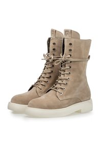 Stivali beige in suede con lacci, a gambale alto, punta rotonda e suola bianca spessa. Presentano occhielli in metallo e un logo sulla linguetta.