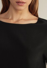 Černý top s hladkou texturou a širokým výstřihem, se krátkými rukávy a elegantním, minimalistickým designem.