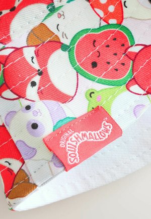 Un tissu coloré présentant des animaux de dessin animé et des fruits, avec une étiquette logo rouge portant l'inscription "Original Squishmallows." Texture matelassée, design ludique.