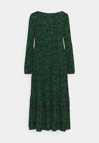 Robe verte à manches longues avec imprimé floral noir, encolure ronde et jupe à volants, suspendue sur un fond blanc.