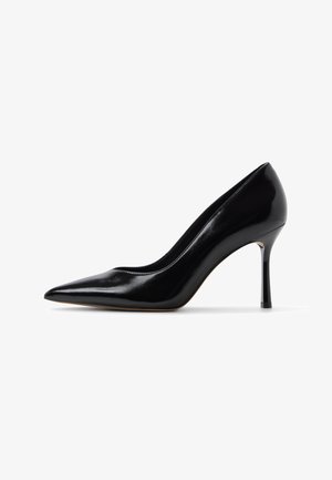 Zwarte lakleren stiletto pump met spitse neus en dunne hoge hak, zijaanzicht op een witte achtergrond.