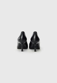 Sorte lærhøye hæler med spiss tå og stiletthæl, med en glatt overflate og minimalistisk design.