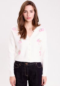 Cardigan blanc cropped avec un col en V, orné de broderies florales colorées en rose et vert, et fermeture à boutons sur le devant.