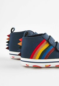 Niebieskie buty typu high-top z sztucznej skóry, zapinane na rzepy, z wielokolorowymi paskami i kolcami na pięcie. Biała gumowa podeszwa.