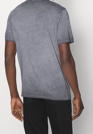 Graues T-Shirt mit kurzen Ärmeln aus weichem Stoff, das ein leicht verblasstes Aussehen und eine lockere Passform aufweist. Die Rückansicht zeigt ein minimalistisches Design.