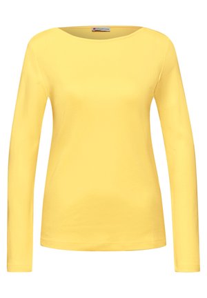 Żółta damska koszula z długim rękawem, o okrągłym dekolcie, prosta w kroju, z małą metką marki wewnątrz kołnierza.