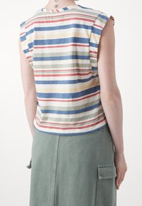 Débardeur rayé beige, avec des rayures horizontales bleues, vertes et rouges. Matière en coton avec une coupe décontractée et un col rond.