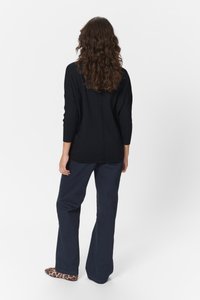 Sort ribbet striktrøje med trekvartærmer, parret med marineblå vide bukser og dyreprint slip-on sko. Set bagfra.