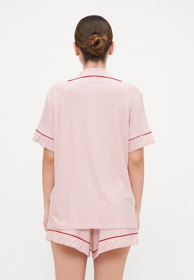 Red and white striped pajamas with short sleeves and shorts, featuring contrasting red trim along the edges. Soft fabric texture.