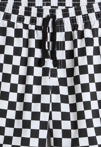 Black and white checkered swim shorts with an elastic waistband and a drawstring. Features a small front opening and smooth texture.