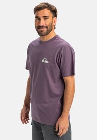 Purple cotton t-shirt with a crew neckline and short sleeves, featuring a small white logo on the chest. No patterns or additional accents.