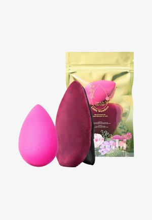 De beauty blender set bevat een roze druppelvormige spons en een bordeaux applicator. Verpakt in een reflecterende gouden tas met bloemenaccenten.