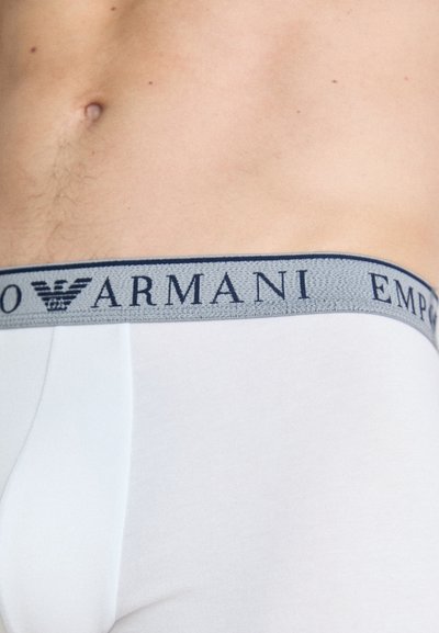 Fehér pamut boxer alsónadrág szürke elasztikus derékpánttal, amelyen navy kék "Emporio Armani" logó található. Simaságával és testhezálló kialakításával jellemző.