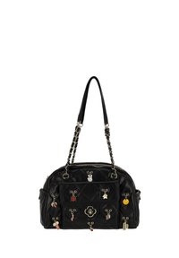 Bolso negro acolchado con forma redondeada, asas de cadena y cuero, decorado con múltiples dijes coloridos y un emblema decorativo en el frente.