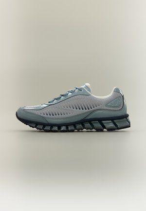 Baskets gris clair avec dessus en mesh ventilé, col rembourré, lacets à l’avant et semelle en caoutchouc noir segmentée vues de profil sur fond neutre.