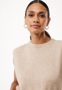 Top beige senza maniche con scollatura rotonda, caratterizzato da una morbida texture e un design minimalista. Dettagli sottili con una finitura liscia.