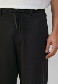 Zwarte broek van zachte stof, met een elastische tailleband, zijzakken en een relaxed fitting, met een gladde textuur en nette lijnen.
