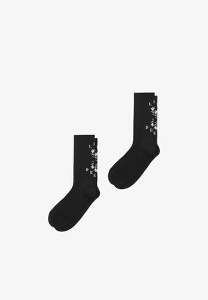 Zwarte katoenen sokken met een geribbelde textuur en een grafisch ontwerp met bladeren en tekst aan de zijkant, voor een comfortabele pasvorm.