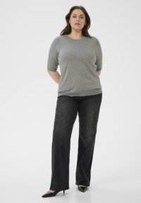 Top gris de manga corta con un escote texturizado, combinado con unos jeans de pierna ancha negros y unos tacones negros de punta. Conjunto sencillo y casual.
