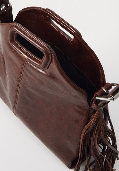 Brown leather handbag with a textured finish, top handles, and a fringe accent. Open top reveals a spacious interior.