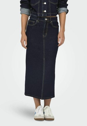 Mörkblå denimmaxikjol med rak skärning, framsömn och detaljer i gul brodering, tillsammans med vita sneakers.