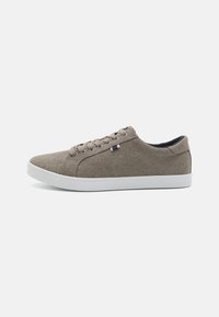 Brown canvas sneakers with a round toe, white rubber sole, and five eyelets. Features a small tri-color accent on the side.