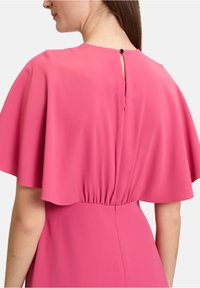 Rosenfarbenes Kleid mit fließendem Umhangärmel-Design, an der Taille gerafft, mit einem kleinen Schlüssellochverschluss hinten und einer schwarzen Knopfverschluss.