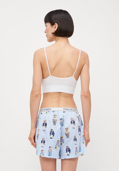 White bralette with thin straps paired with blue patterned boxers featuring cartoon bears on a striped background. Elastic waistband visible.
