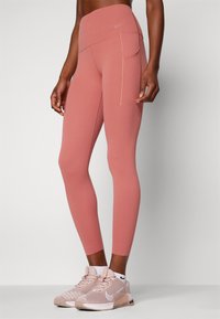 Nike leggingai švelnios rožinės spalvos, aukšta juosmeniu, su plokšiomis siūlėmis, šoniniu kišeniu, pagaminti iš tamprus, drėgmę sugeriančios medžiagos.