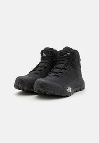 Black hiking boots with a high-top design. Made from synthetic materials, featuring textured surfaces, robust soles, and reinforced eyelets.