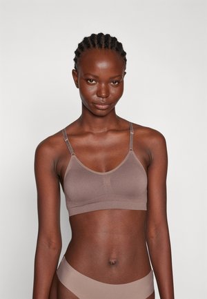 Brun sømløs bralette med justerbare stropper, rund utskjæring og en myk tekstur. Har minimal søm og en jevn overflate.