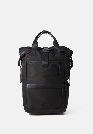 Mochila de tecido preta com acabamentos em pele texturizada, design de topo enrolado, dois zíperes frontais e alças ajustáveis. Estilo minimalista.