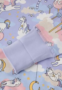 Paarse stof met een speels eenhoornpatroon, met wolken en sterren. Een stuk solide lavendelkleurige stof met een textuurafwerking is zichtbaar.
